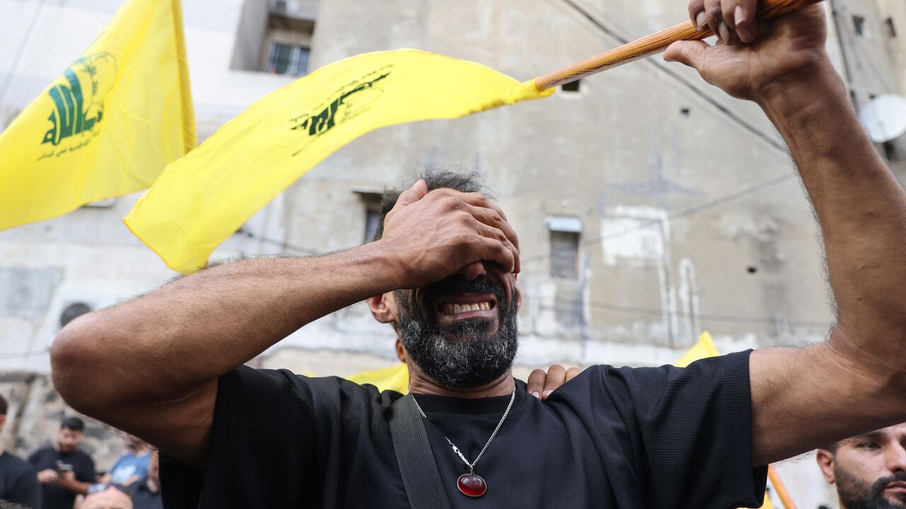 A man reacts while holding a Hezbollah flag during the funeral of people killed after hundreds of paging devices exploded in a deadly wave across Lebanon the previous day in a south Beirut district on Sept. 18, 2024.